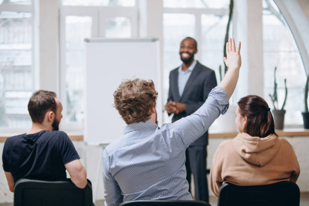 istock Male speaker giving presentation in hall at workshop. Audience or conference hall. Rear view of unrecognized participants. 1299240350