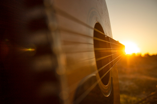 Image was taken during the golden hour,just an hour before the sundown,of an acoustic guitar wich its chords leads people's eye straight to the sunset.