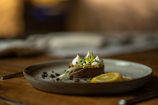 Well decorated tart cake on wooden table on plate in restaurant