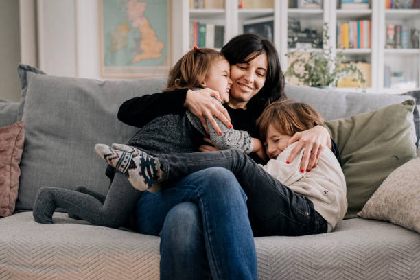 istock Mother cuddles her children at home 1299242148