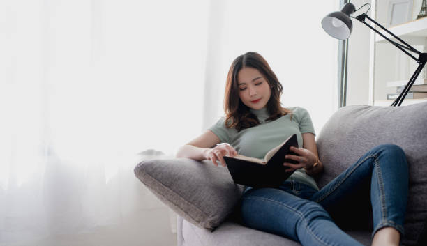 istock An optimistic woman is happy. She sits on the sofa and reads a book. 1299244228