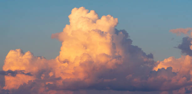 eine riesige weiß-rosa volumetwolke am blauen himmel. - cumuliform stock-fotos und bilder