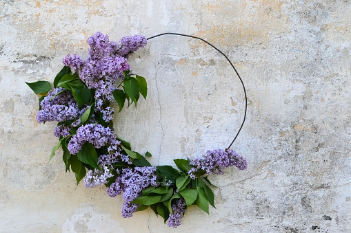 Festive wreath with lilac flowers. Wedding, birthday, Valentine's day, easter, mothers day concept. Beautiful DIY natural wreath on gray rustic background. Flat lay, top view