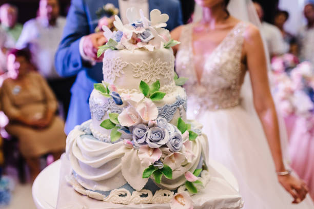 Bride and a groom is cutting their rustic wedding cake on wedding banquet. Hands cut the cake with delicate flowers. Bride and a groom is cutting their rustic wedding cake on wedding banquet. Hands cut the cake with delicate flowers. wedding cake stock pictures, royalty-free photos & images