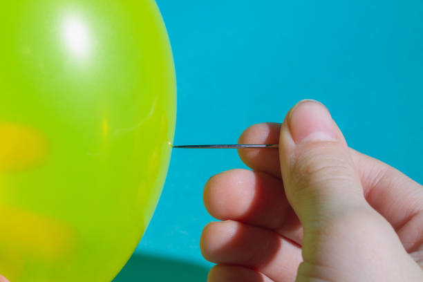 istock Pop the balloon with a sharp needle. Hold the sewing needle in your hand 1299251968