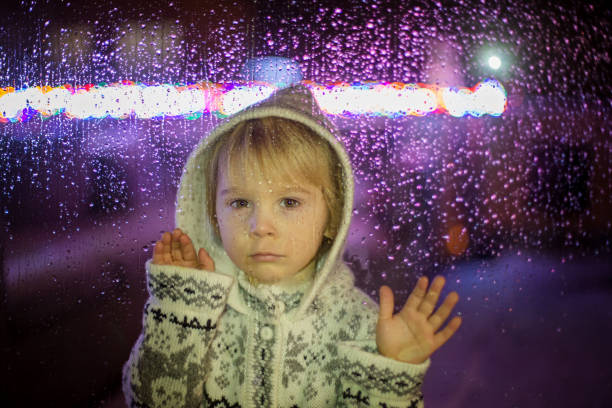 litet barn, småbarnspojke, stående bakom fönster med droppar utomhus i snön - children tree christmas silhouette bildbanksfoton och bilder