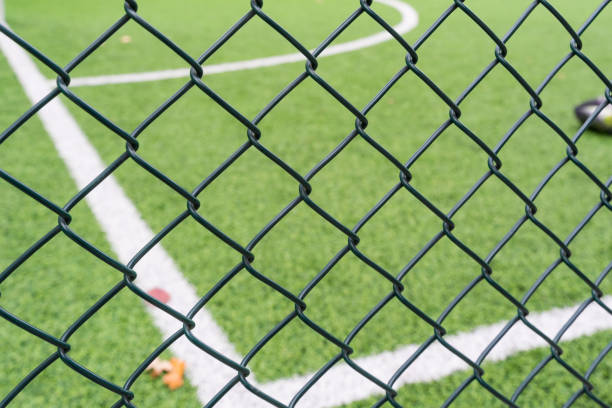 Fence netting close-up on a background of a soccer field.