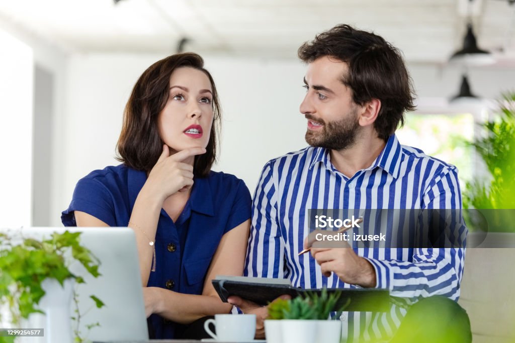 Coworkers working in the eco-friendly green office Mid adult women and man sitting on sofa in the creative workplace and working together, discussing agenda. 30-39 Years Stock Photo