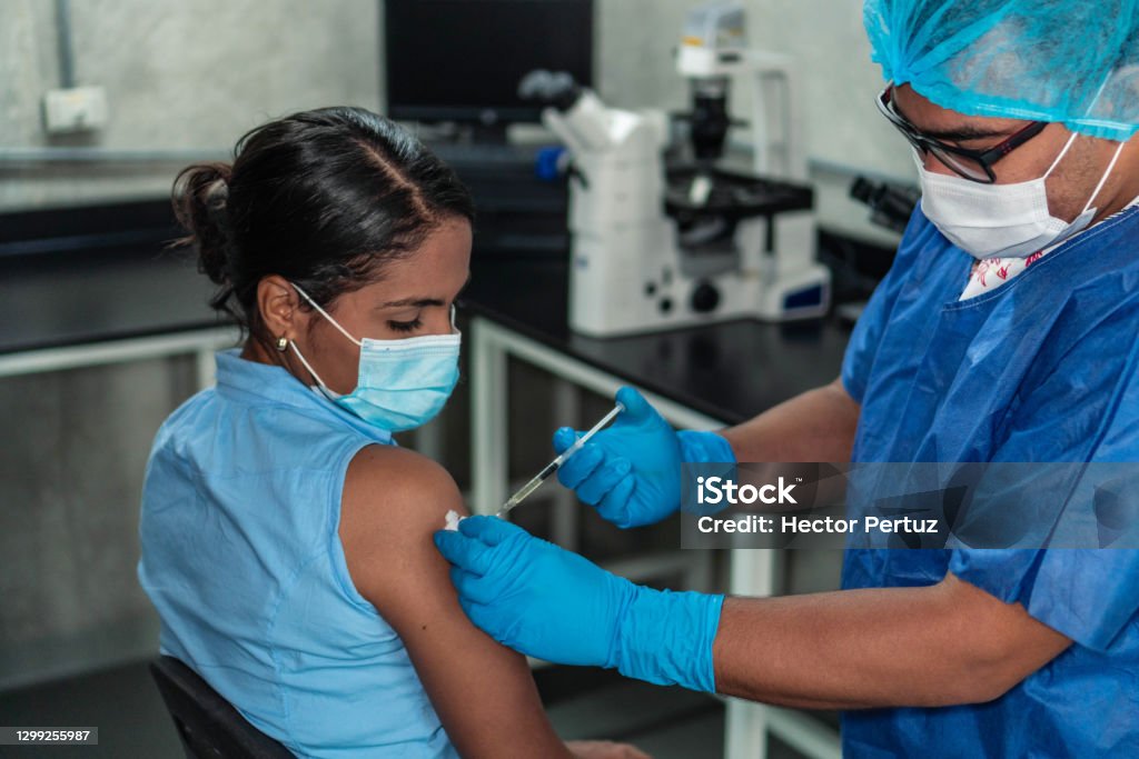 Young woman receiving coronavirus vaccine Hispanic woman receiving coronavirus vaccine Vaccination Stock Photo