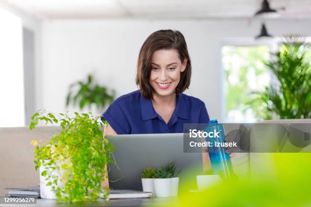 Smiling Woman Working On Laptop At Home Stock Photo - Download Image Now - Laptop, Water Bottle, 30-39 Years