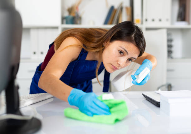istock Mexican woman wearing uniform cleaning table in office 1299256336