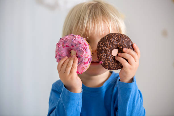 istock Cute sweet blonde child, playing and eating donuts 1299256405