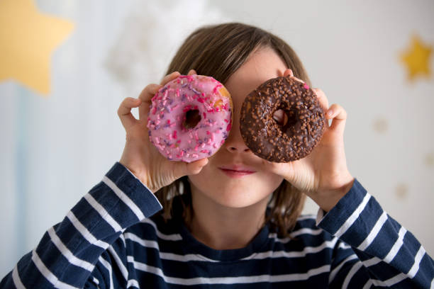 istock Cute sweet blonde child, playing and eating donuts 1299256463