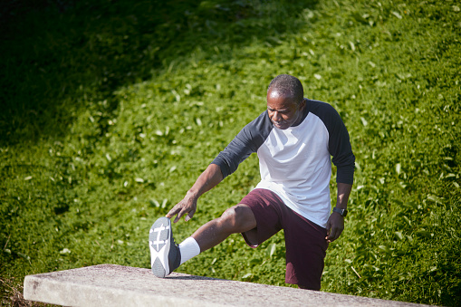 Senior active african-american man stretching leg outdoors at park