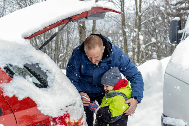 istock Father and son removing snow and ice off their car. 1299260373
