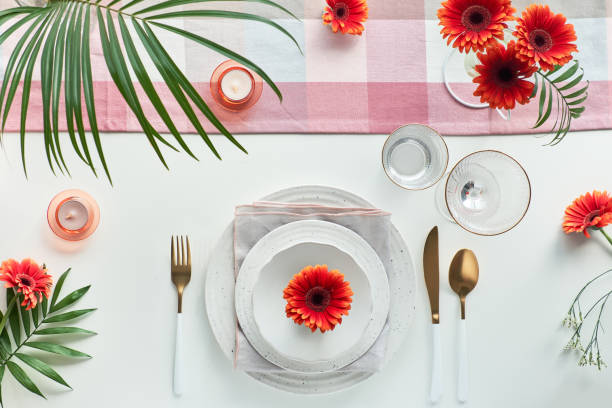 istock Effortless golden birthday dinner table decor. Vibrant Summer flat lay. White dinner table, white and gold utensils, decorated with peony flowers, orange gerberas and tasty apricots 1299260524