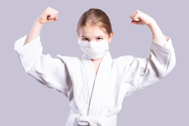 Girl in a kimono judo. Shows strength. Isolated on gray background. stock photo