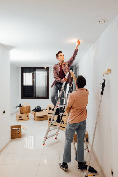 istock Young couple moving in new house, changing a light bulb. 1299261979