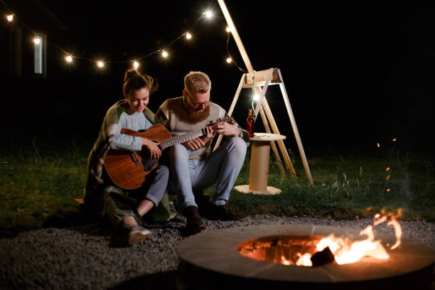 istock Man teaching girl play a guitar on autumn night picnic 1299262900