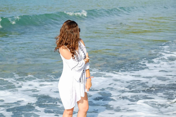 istock one red-haired beautiful girl stands on the beach 1299263213