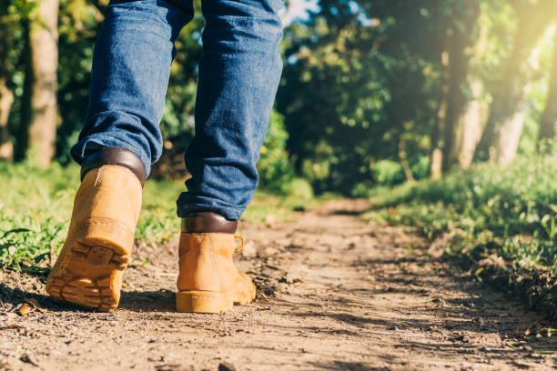 pieds d’un adulte portant des bottes pour voyager marchant dans une forêt verte. concept de voyage et de randonnée. - ski pants photos et images de collection