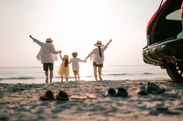 vacaciones en familia, feliz familia corriendo en la playa en la puesta de sol. vista trasera de una familia feliz en una playa tropical y un coche en el lado. - summer fotografías e imágenes de stock