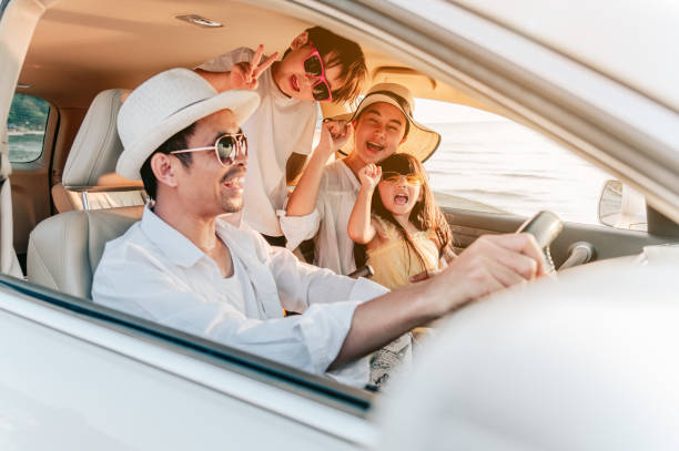 Portrait of  family enjoying beach trip with their favorite car. Parents and children are traveling the way to the sea.Holiday and travel family concept, Summer vacations. stock photo