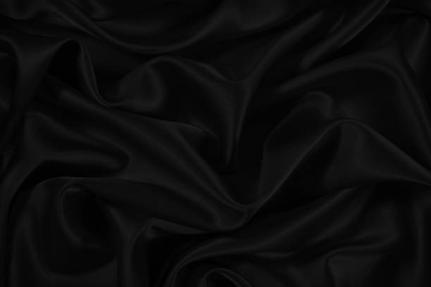 istock Beautiful silk satin background. Black smooth fabric with soft wavy folds. Elegant abstract background with copy space for your design. 1299269123