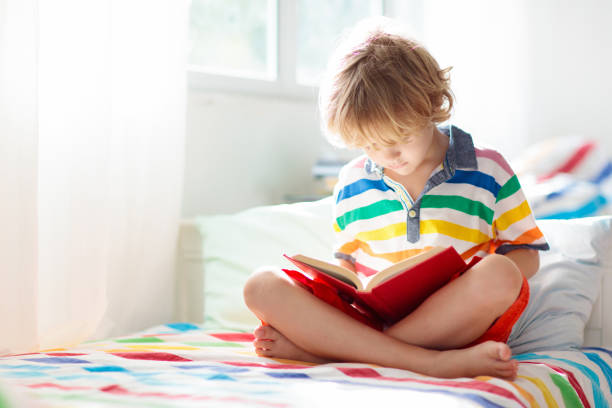 istock Child reading book in bed. Kids read in bedroom. 1299270788