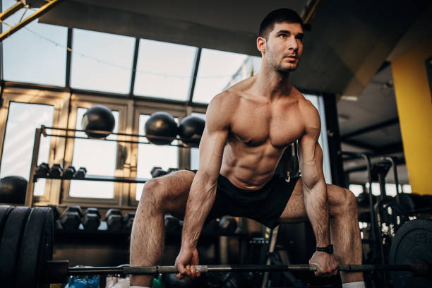 istock Muscular shirtless man exercising with weights in gym 1299271607