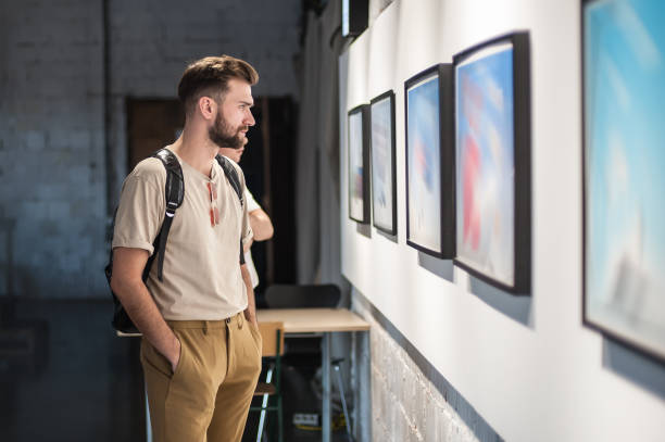 Young man in modern art exhibition gallery hall Young man in modern art exhibition gallery hall contemplating artwork. Abstract painting museum stock pictures, royalty-free photos & images