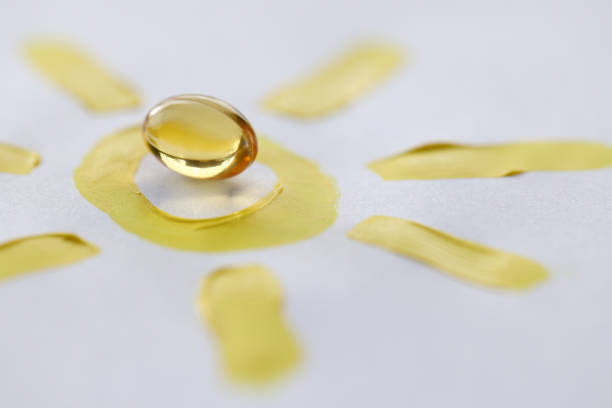 Yellow transparent vitamin D pill lying on drawn sun closeup Yellow transparent vitamin D pill lying on drawn sun closeup. Prevention of rickets concept omega 3 and 6 stock pictures, royalty-free photos & images