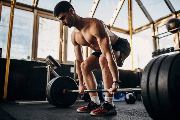 istock Muscular shirtless man exercising with weights in gym 1299274515