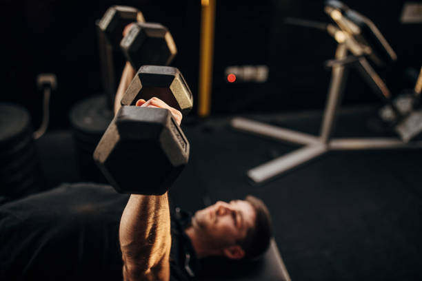 istock Muscular man exercising on weight with dumbbells 1299275176