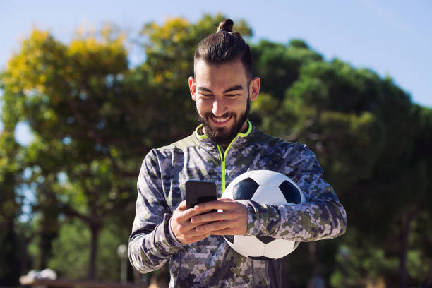 esportista feliz escrevendo uma mensagem em seu telefone - treinador desportivo - fotografias e filmes do acervo