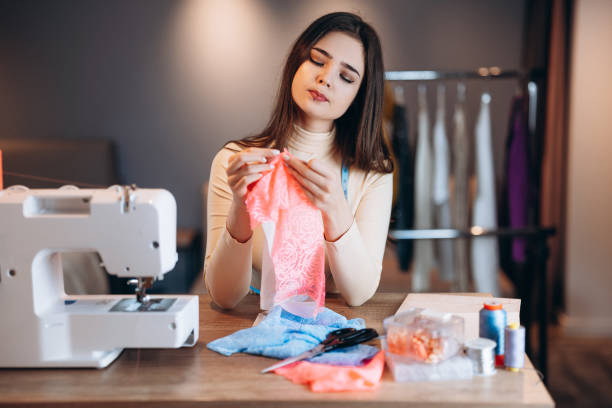 istock Young dressmaker woman sews clothes on sewing machine. Using a needle seamstress in workshop. Creating online clothing design courses 1299276022