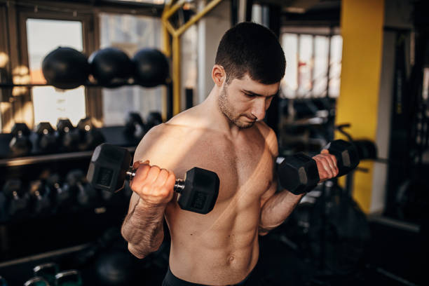 istock Muscular shirtless man exercising with dumbbells 1299276317