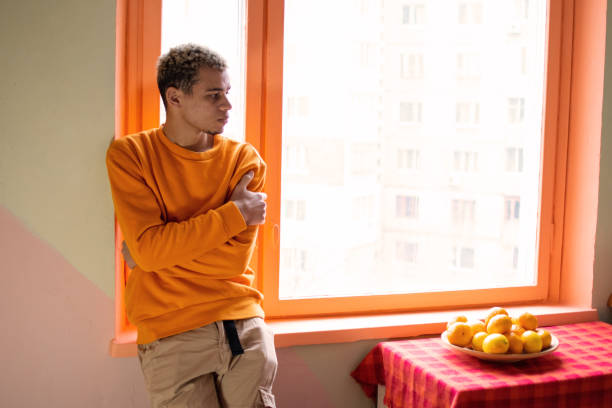 young african american man at home with yellow fruits - orange wall imagens e fotografias de stock