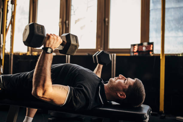 istock Muscular man exercising on weight with dumbbells 1299277630