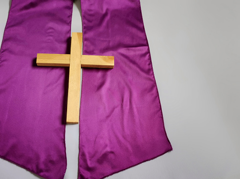 Wooden cross image with purple stole icon. Flat lay with vintage background. Stock photo.