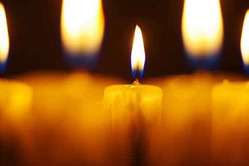 Stock photo showing elevated view of lit diya (oil lamp), with flickering flame in the dark, part of Diwali festival of lights celebration.