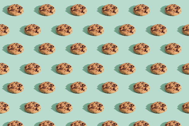 Pattern made of chocolate chip cookies on green mint background