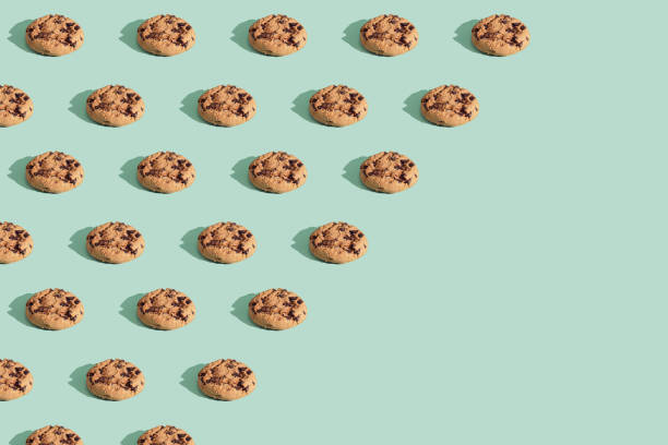istock Trendy pattern made  of chocolate chip cookies on bright green mint background. 1299279046