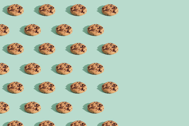 istock Modern pattern made of chocolate chip cookies on green mint background. 1299279061