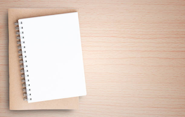 istock Blank paper notebook on brown wooden table background 1299279339