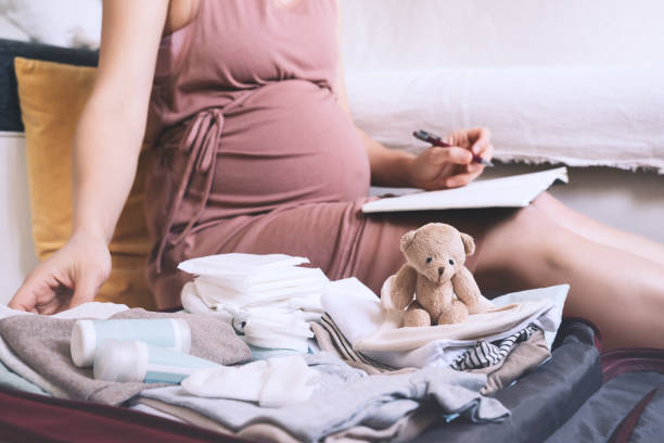 istock Pregnant woman packing bag for maternity hospital, making notes, checking list in diary. 1299281846