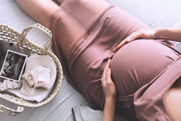 pregnant woman in dress holds hands on belly. mother with wicker basket with stuff for newborn, ultrasound image and teddy toy. - nature human pregnancy color image photography imagens e fotografias de stock