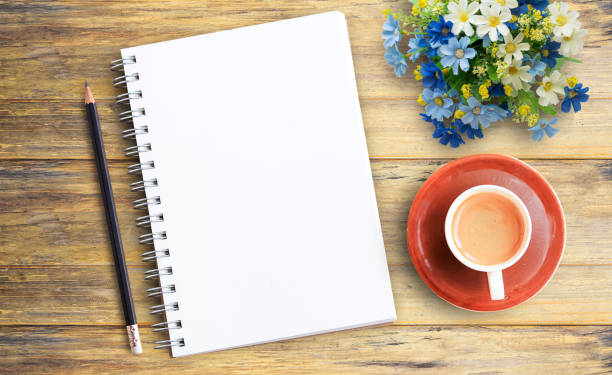 istock Top view image of blank notebook and cup of coffee on wooden table 1299286467
