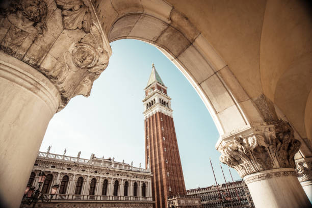 イタリア、ヴェネツィアセンターの建築アーチを通して見たサンマルコタワー - facade palace grand canal canal ストックフォトと画像