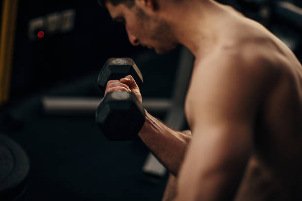 istock Muscular shirtless man exercising with dumbbell 1299287347